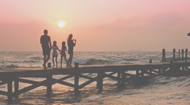 Family of Four on Pier at Beach During Sunset