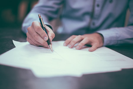 Close Up of a man Signing Documents on a Table